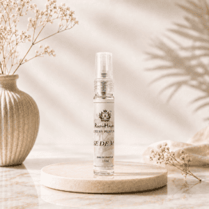 RocheHayatt Rose De Musk 10ml Eau De Parfum travel spray bottle displayed on a cream marble podium with a soft beige floral background, creating a luxurious and elegant product presentation.