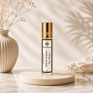 RocheHayatt Tom Down 6ml roll on perfume bottle with gold cap displayed on a beige marble podium in a luxury minimalist background.